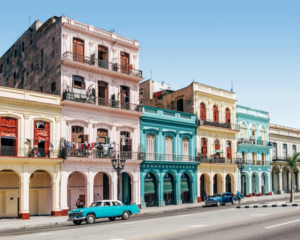 Classic blue American cars parked along a street lined with colorful colonial buildings in Havana