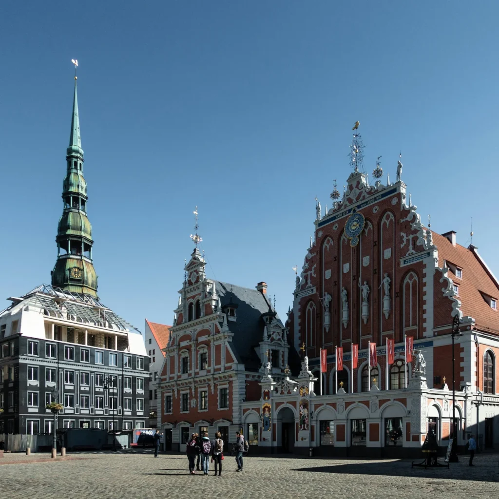 Ornate red brick facade of House of the Blackheads next to St. Peter's Church spire in Riga