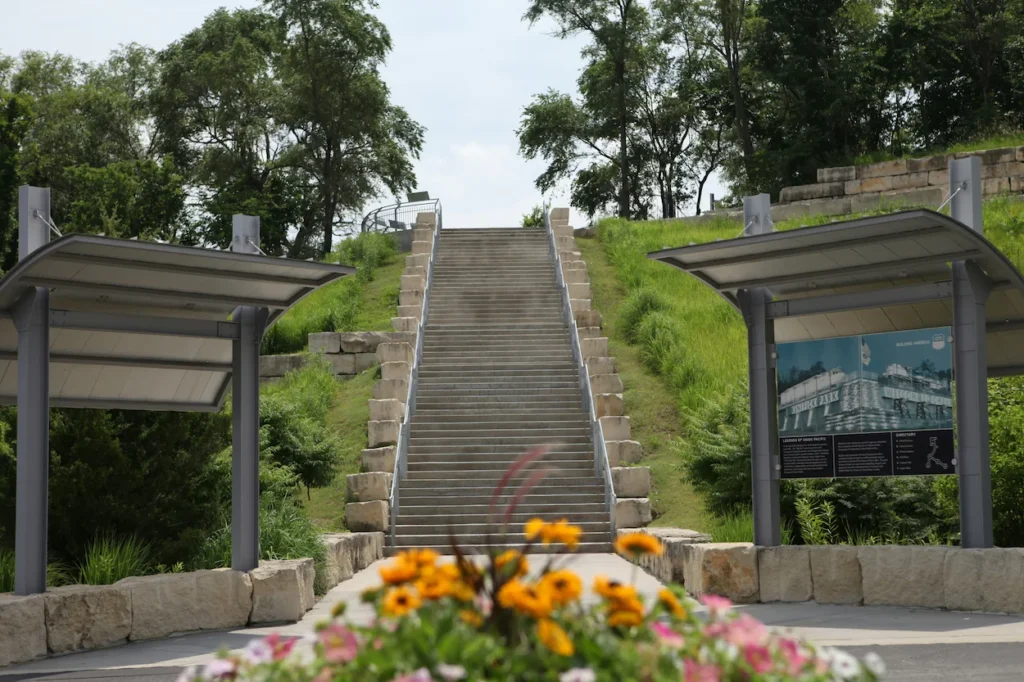 Concrete park staircase leading up a grassy hill between two covered visitor information signs