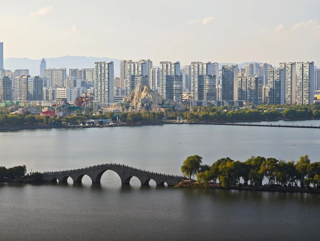 Traditional multi-arch stone bridge spanning Kunming Lake with a dense city skyline behind