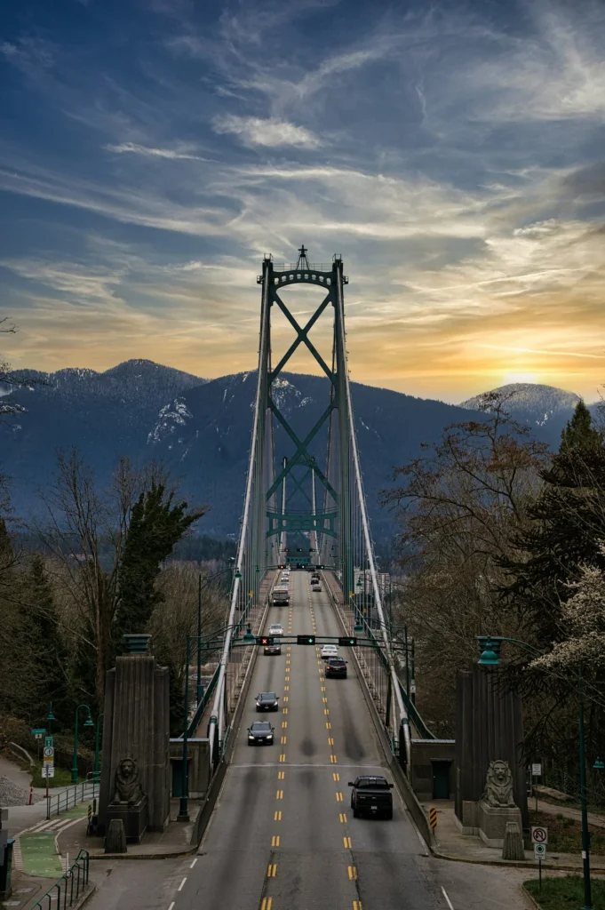 Cars driving on the green Lions Gate suspension bridge at sunset