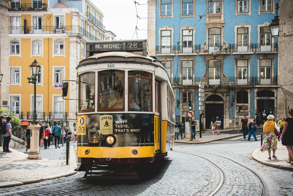 Historic yellow Tram 28 rounding a bend on a cobblestone street in Lisbon