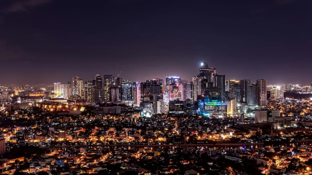 Illuminated Makati skyscrapers tower over residential districts at night