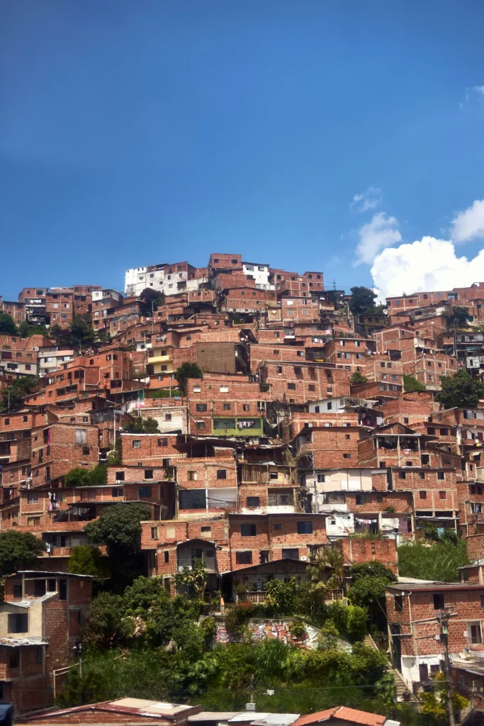Densely packed brick houses built onto a steep hillside in Medellín under a blue sky