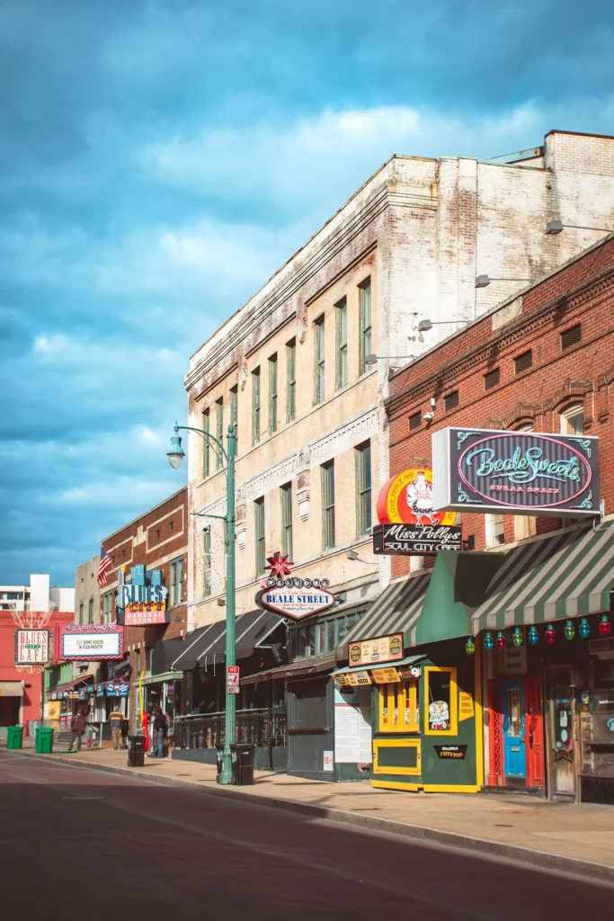 Memphis Beale Street storefronts and neon signs under a cloudy blue sky