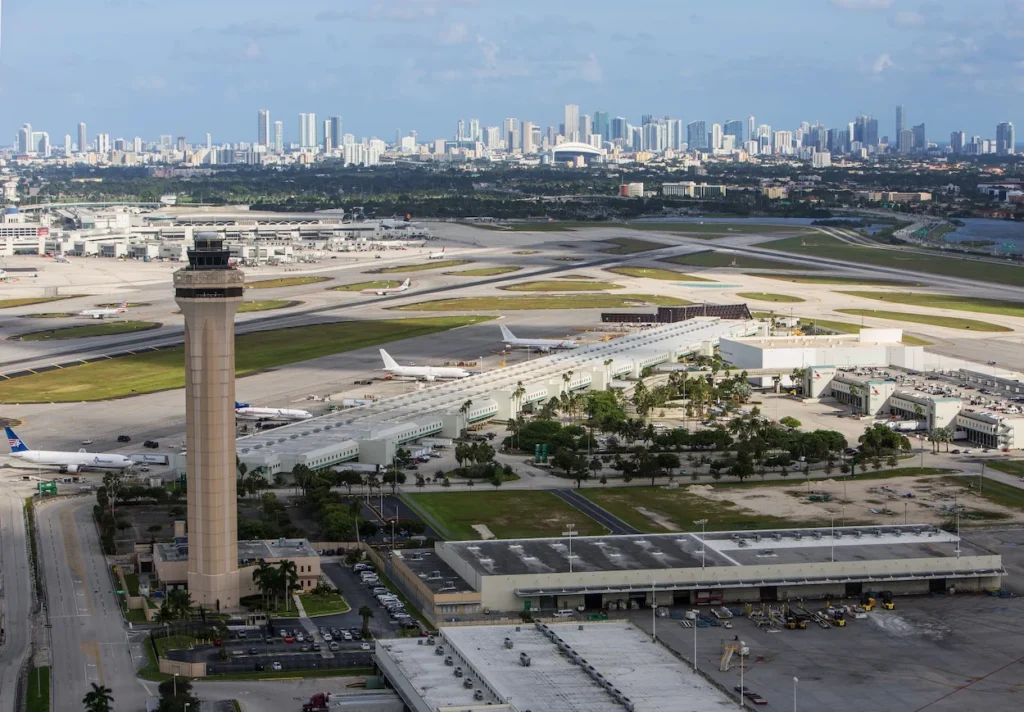 An aerial view of the Miami Airport runways and control tower with the downtown city skyline behind