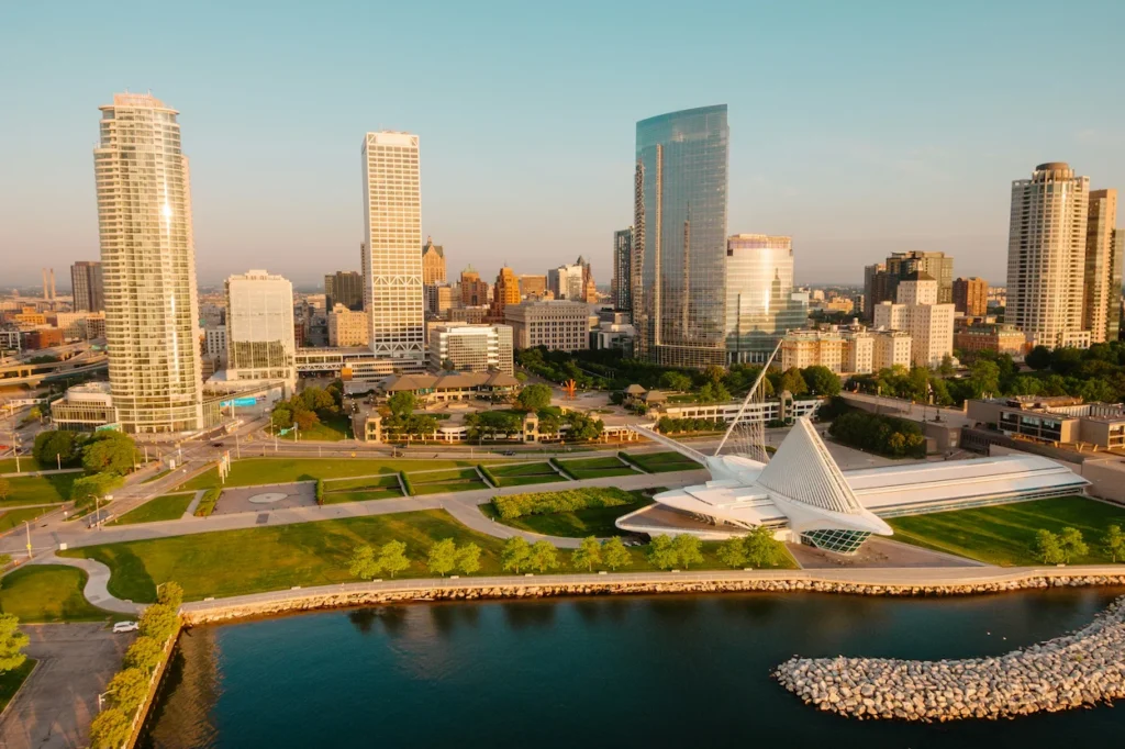 High-angle view of Milwaukee skyscrapers and the white, wing-like art museum structure along a grassy lakefront harbor