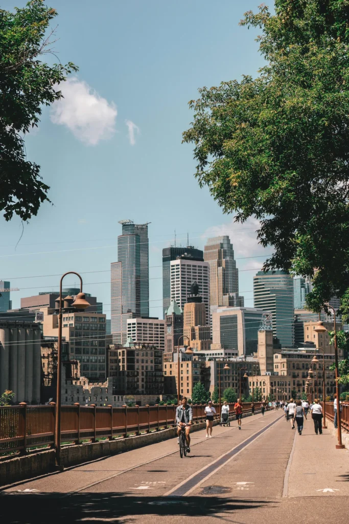 People walking and biking on the Stone Arch Bridge with the Minneapolis skyline behind them