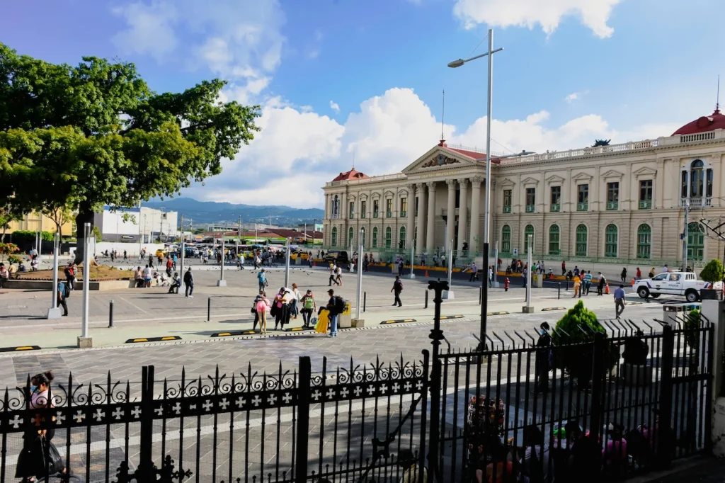 Grand facade of the National Palace building facing a sunny public plaza in El Salvador