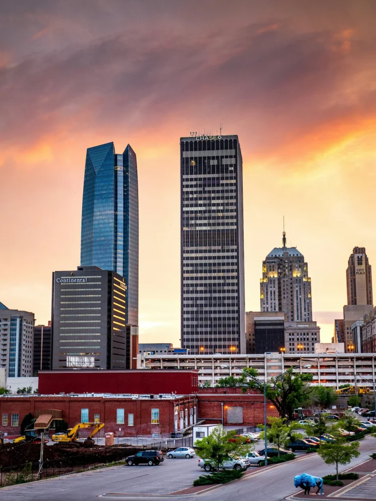 Oklahoma City skyscrapers including Devon Tower and Chase Tower against a vibrant orange and pink sunset sky