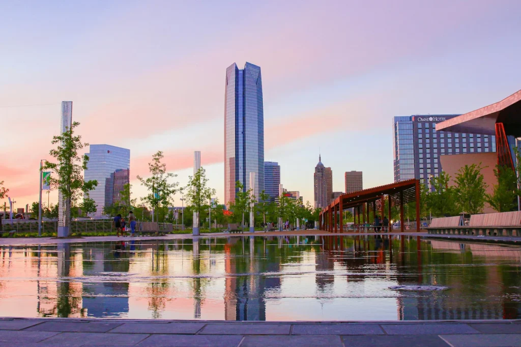 Oklahoma City downtown skyline reflecting in a large water feature at Scissortail Park during a pink sunset