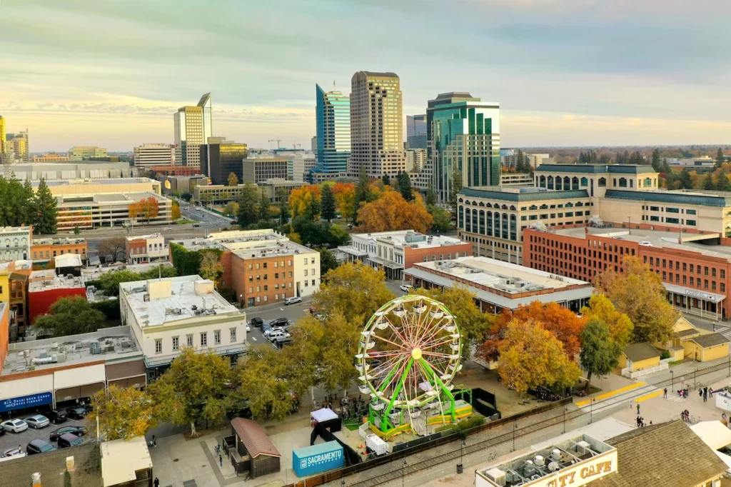A Ferris wheel at Old Sacramento Waterfront with downtown skyscrapers behind it