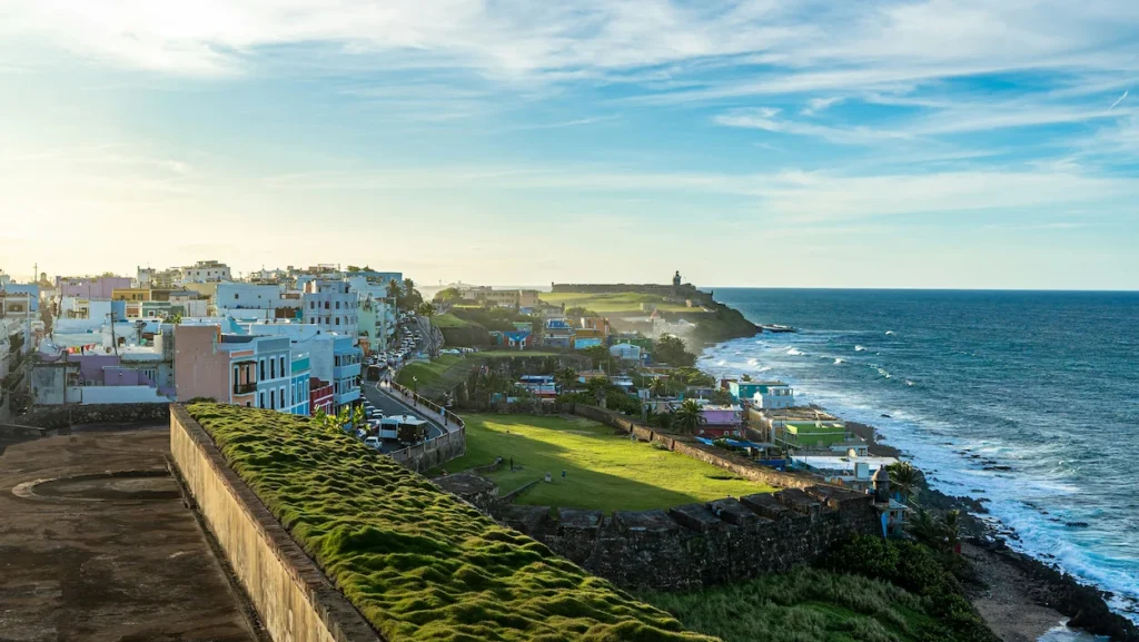 Old San Juan coastline with historic walls, green fields, and colorful buildings by the ocean
