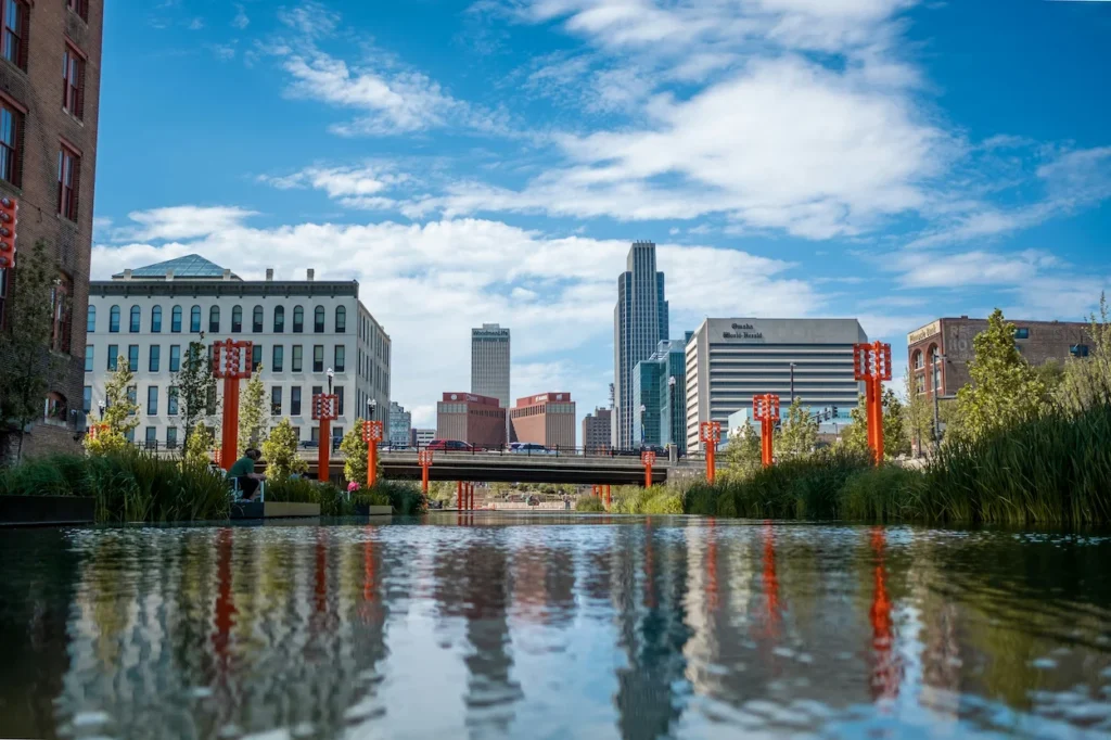 Omaha skyscrapers and skyline reflecting in the Gene Leahy Mall lagoon water under blue sky