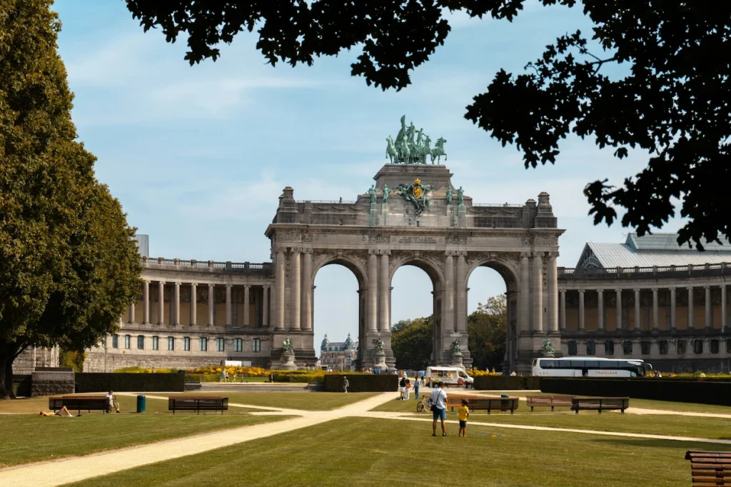 Massive stone triple triumphal arch topped with a bronze chariot statue in a Brussels park