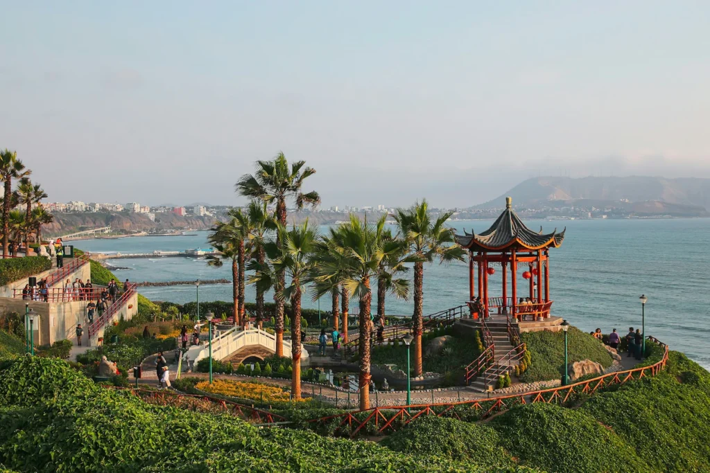Traditional red Chinese pavilion and palm trees on the green Miraflores cliffs overlooking the Pacific Ocean in Lima