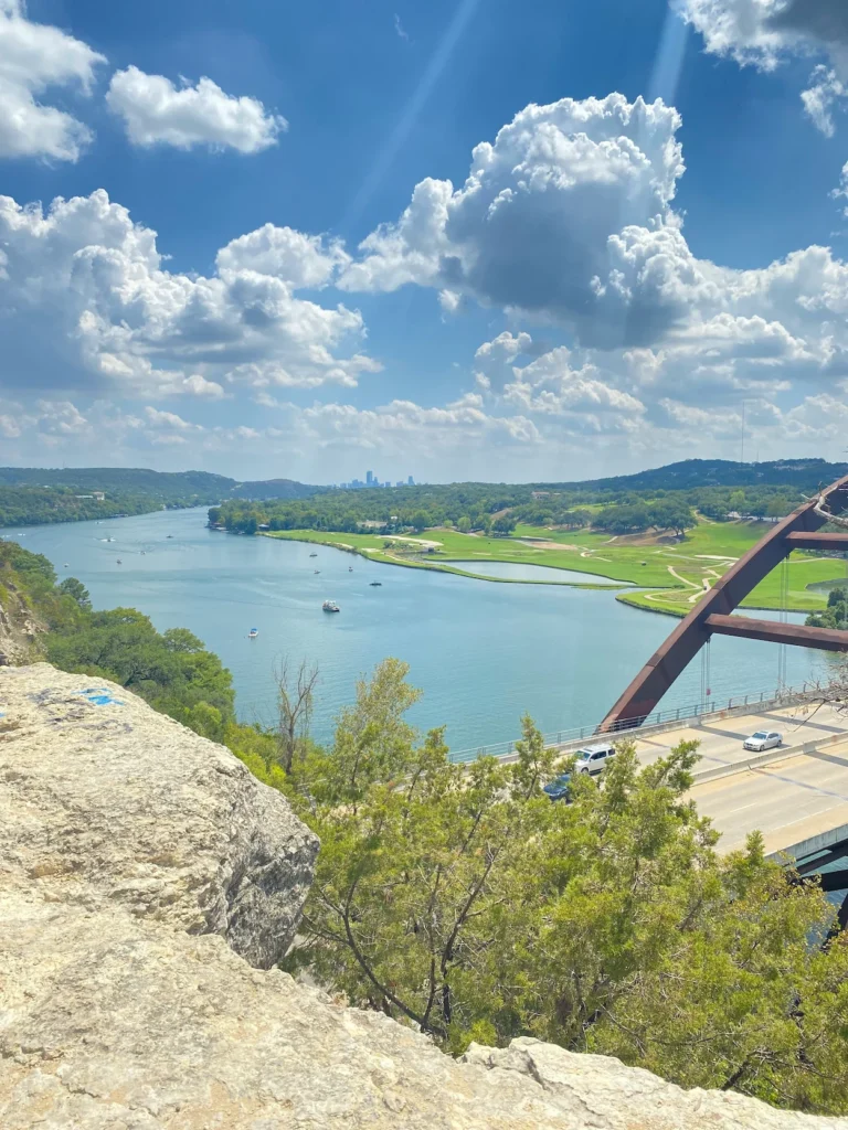 Pennybacker Bridge crossing Lake Austin with the distant city skyline under a cloudy sky