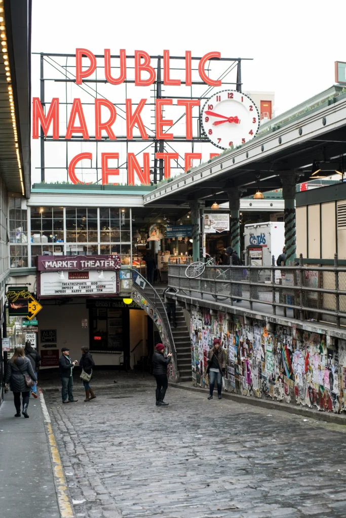 The neon Public Market Center sign over a cobblestone alleyway entrance at Pike Place Market