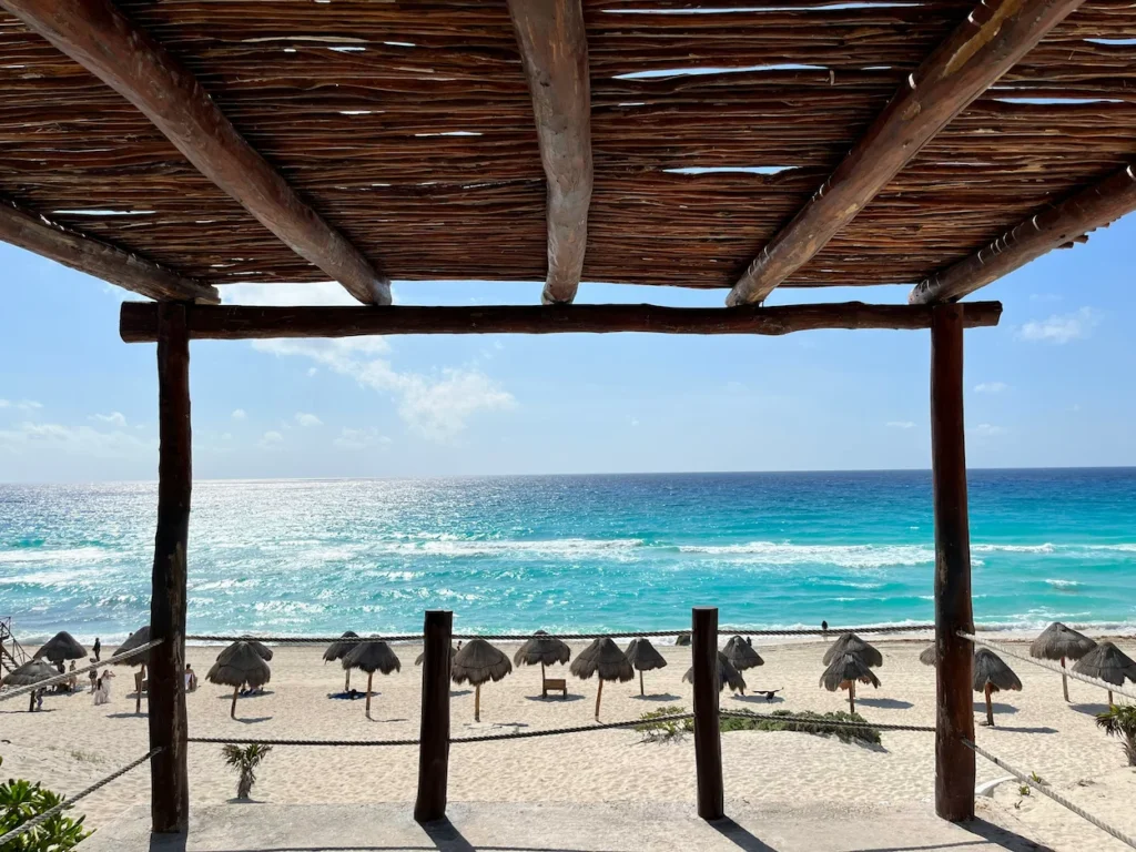 View of the turquoise ocean at Playa Delfines through a wooden shade structure