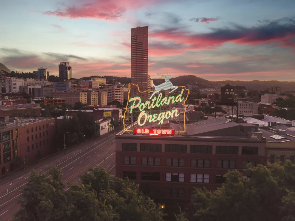 Illuminated neon White Stag Oregon sign against the Portland skyline