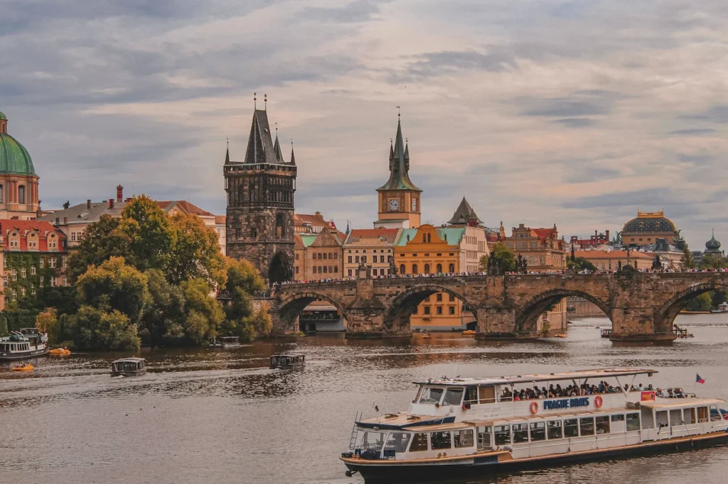 A tourist boat on the Vltava River in front of the historic Charles Bridge in Prague