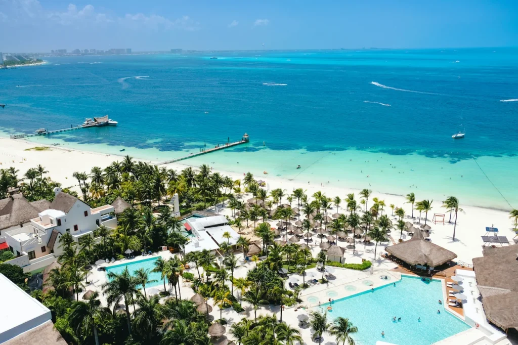 An aerial view of the pools, white sand beach, and docks at Presidente Intercontinental Cancun Resort
