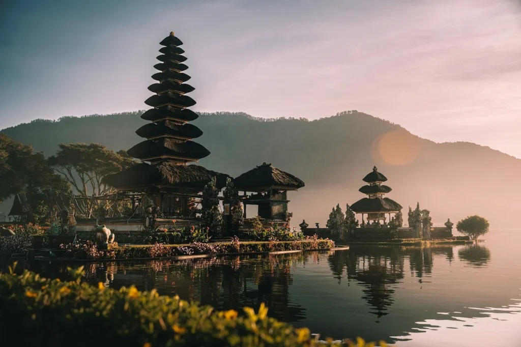 Multi-tiered pagodas of Pura Ulun Danu Bratan temple reflecting on a calm lake at sunrise