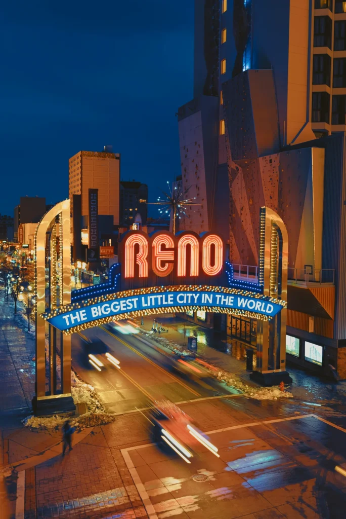 The illuminated neon Reno Arch spanning a city street at night with motion-blurred car headlights