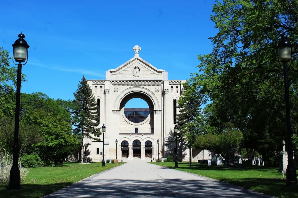 Stone facade and open rose window structure of Saint Boniface Cathedral seen from a paved walkway