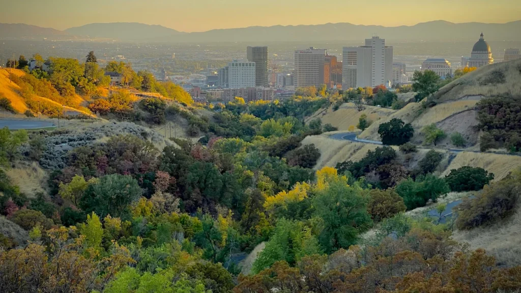 Salt Lake City skyline and Utah State Capitol dome viewed through rolling canyon hills at sunset