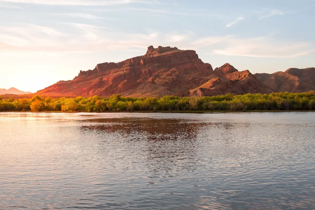 Vibrant red rock mountain reflecting perfectly on the calm waters of the Salt River in Arizona