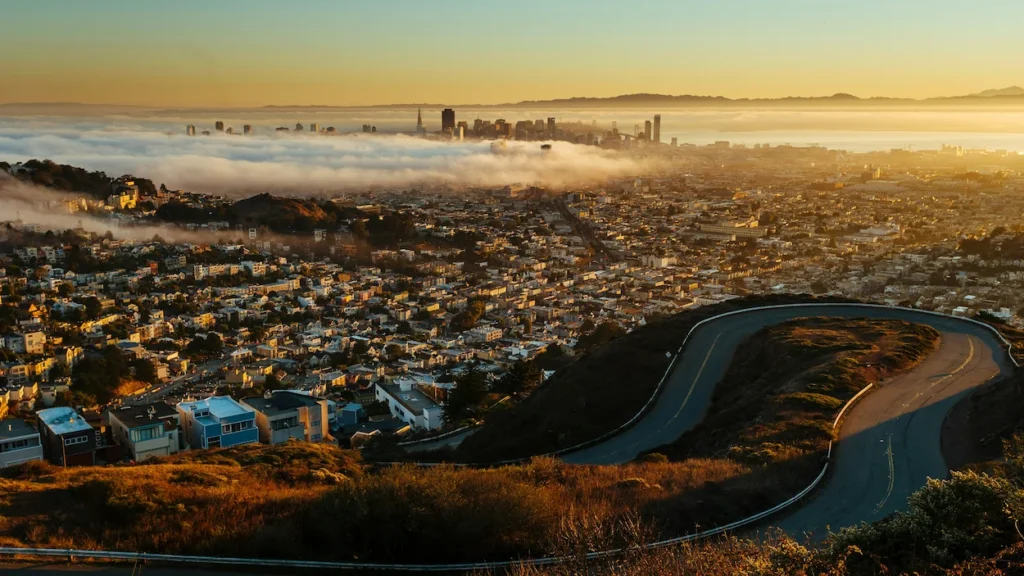 Winding road on Twin Peaks overlooking a foggy San Francisco skyline at sunrise