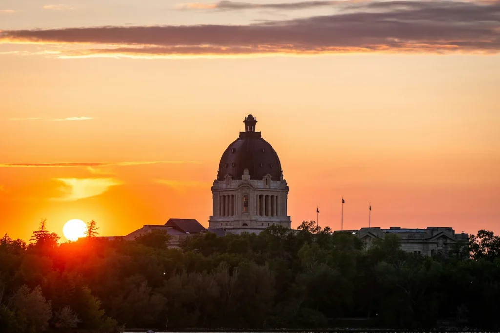 Saskatchewan Legislative Building dome silhouetted against a bright orange prairie sunset