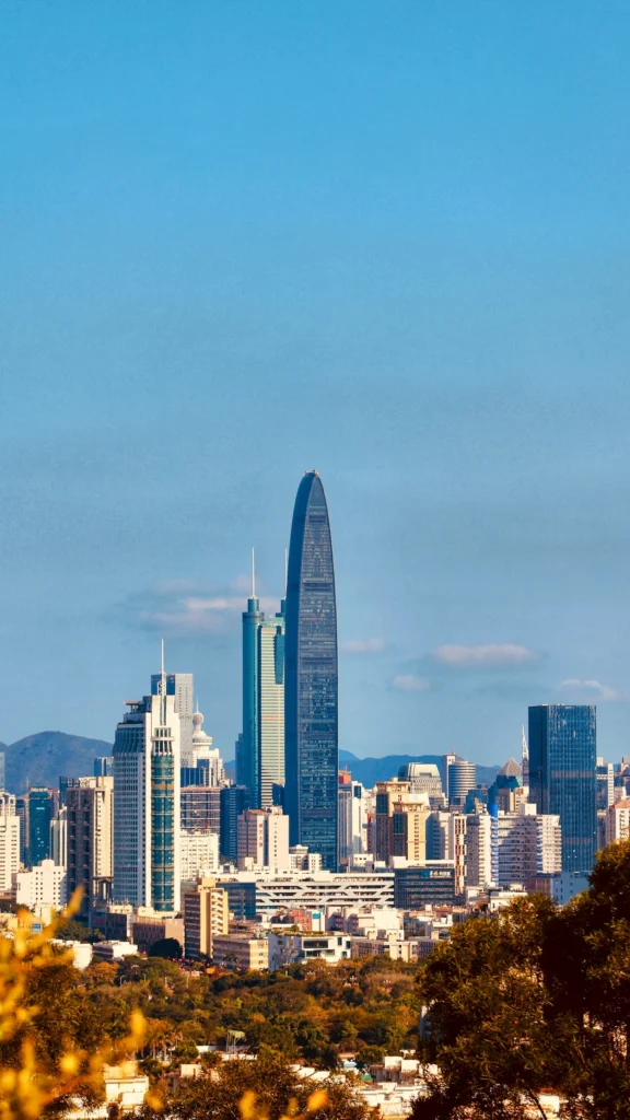 Iconic KK100 skyscraper soaring above the Shenzhen city skyline against a clear blue sky
