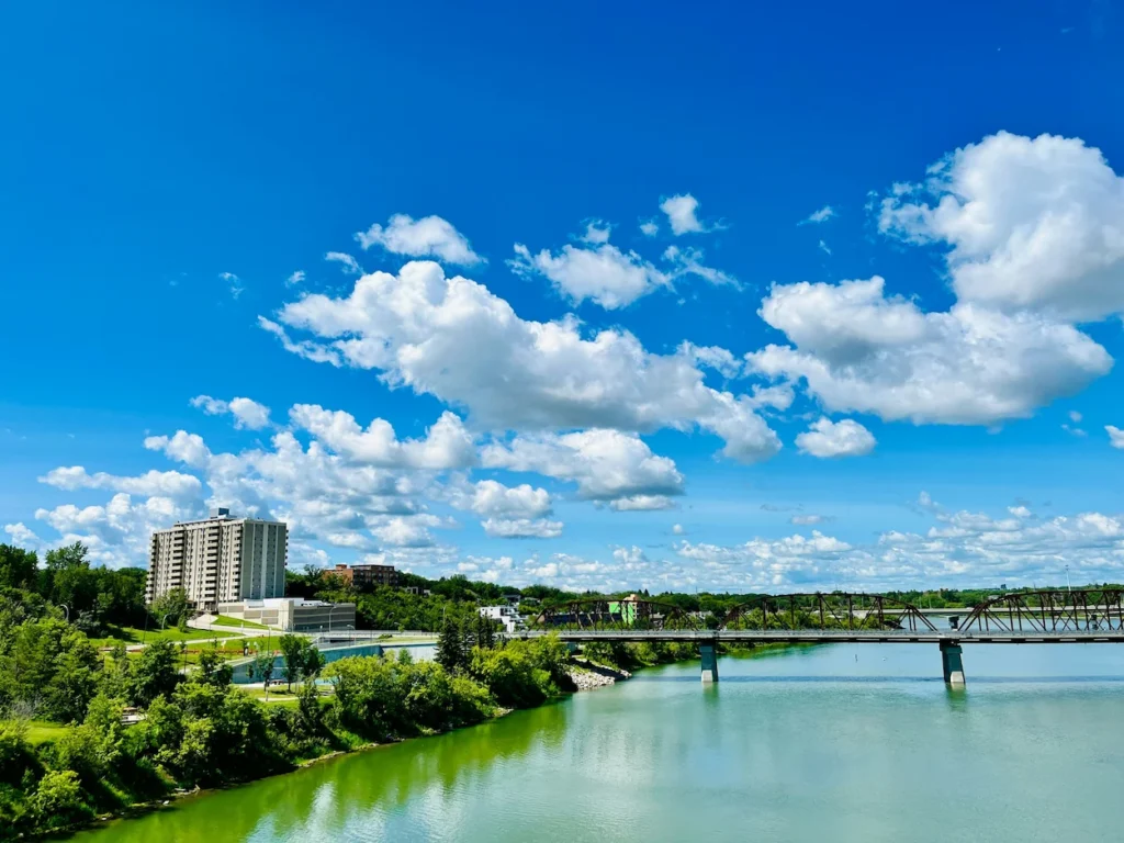 Steel Broadway Bridge spanning South Saskatchewan River under a bright blue sky