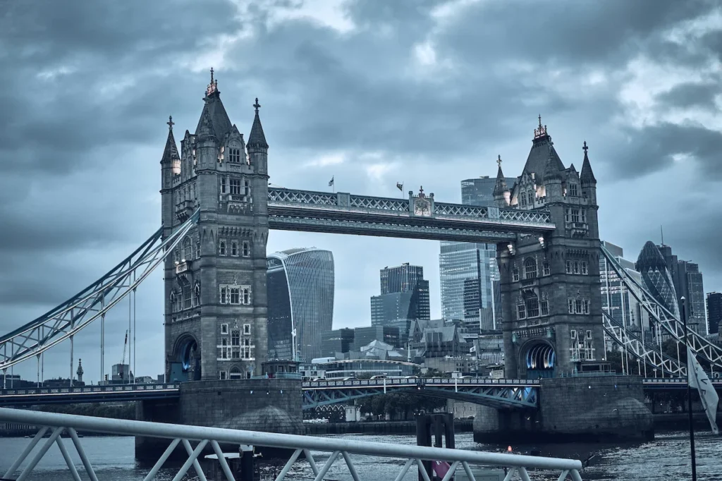 Tower Bridge over the River Thames with London city skyscrapers under overcast clouds