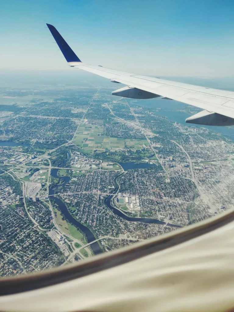 United Airlines airplane wing with blue winglet flying over a city view from a cabin window