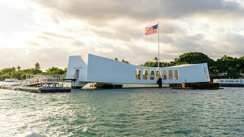 USS Arizona Memorial spanning the water at Pearl Harbor with an American flag flying
