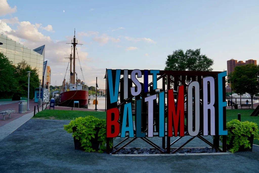 The large colorful Visit Baltimore sign on the Inner Harbor waterfront path in Baltimore