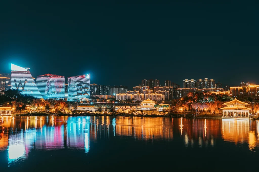 Xi'an Qujiang Pool Park skyline at night with W Hotel and illuminated traditional pavilions reflecting on water