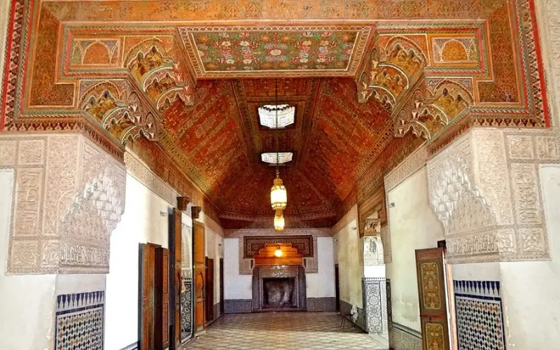 Ornate interior hall with carved arches and painted ceiling at Bahia Palace in Marrakech.