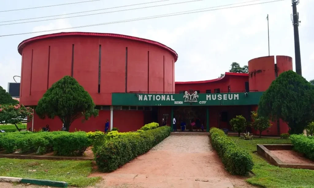 The front entrance of the National Museum in Benin City with red walls and green signage.