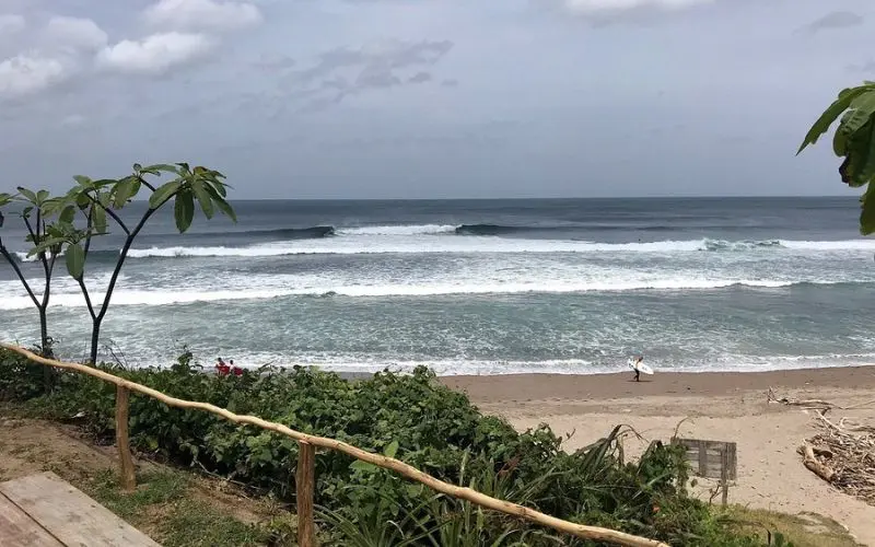Surfer walking along the sandy beach at Popoyo.