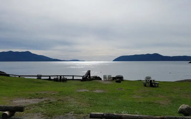 Grassy shoreline with picnic tables overlooking the water at Doe Bay Hot Springs.