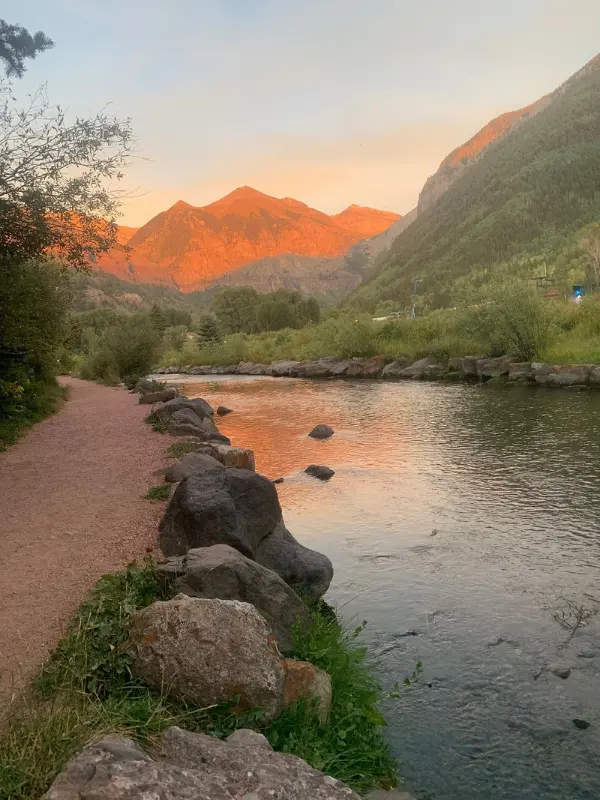 The San Miguel River at sunset with mountains glowing in the background.