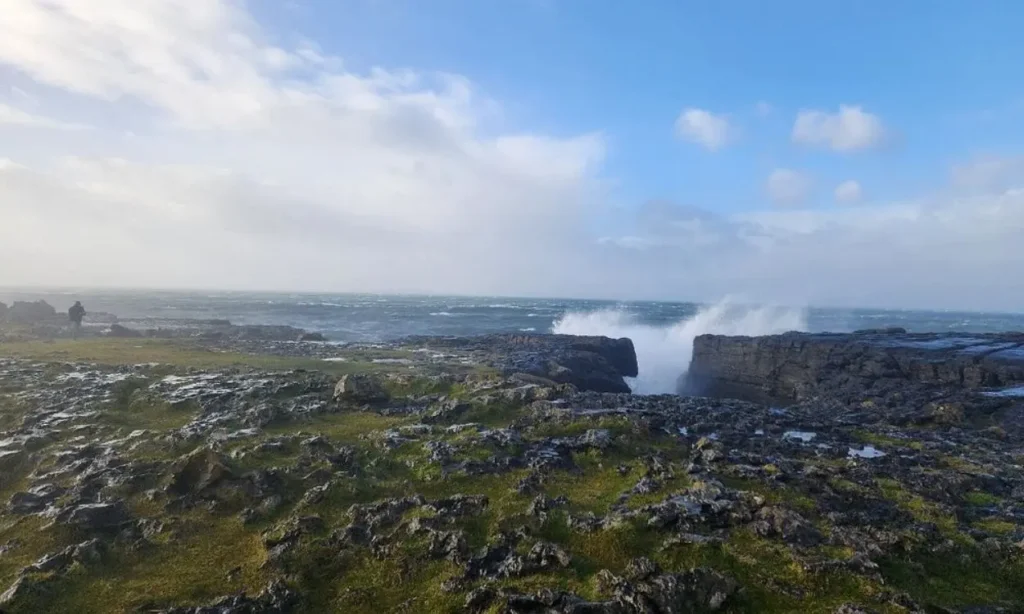 The Burren has a rocky coastal landscape with waves crashing against the shore.
