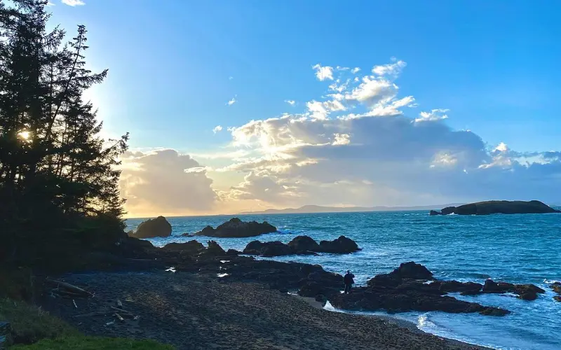 Sunset over waves and rocky shoreline at Rosario Beach.