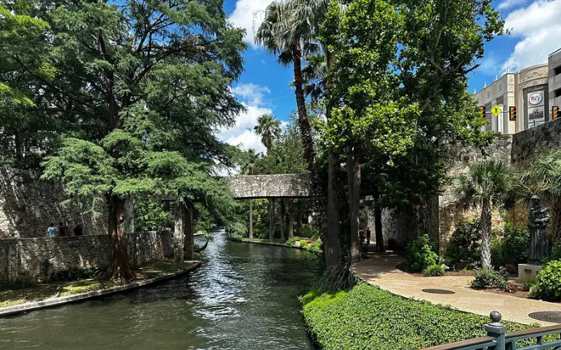 Tree-lined San Antonio River Walk with pathways and bridges.