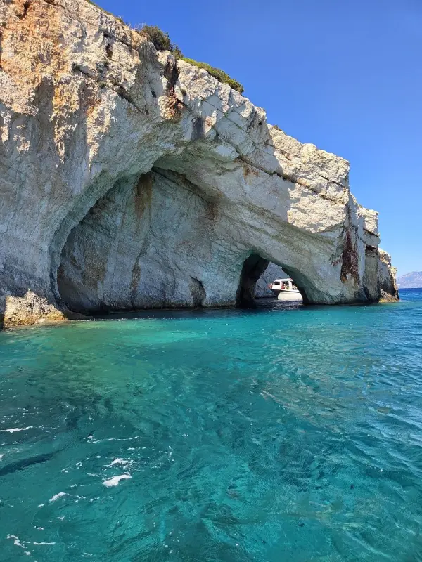 White cliffs with sea caves and a boat at the Blue Caves.