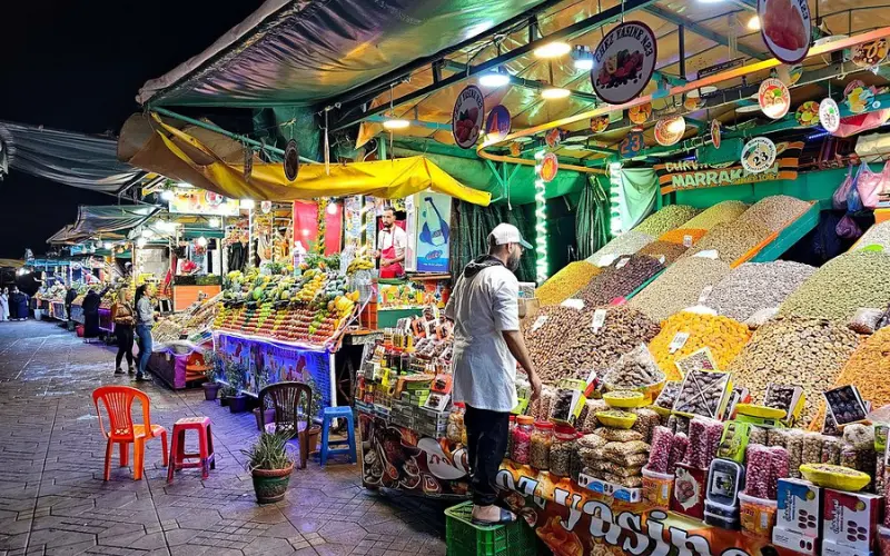 Colorful night market stalls selling food and goods at Djemaa el-Fna in Marrakech.
